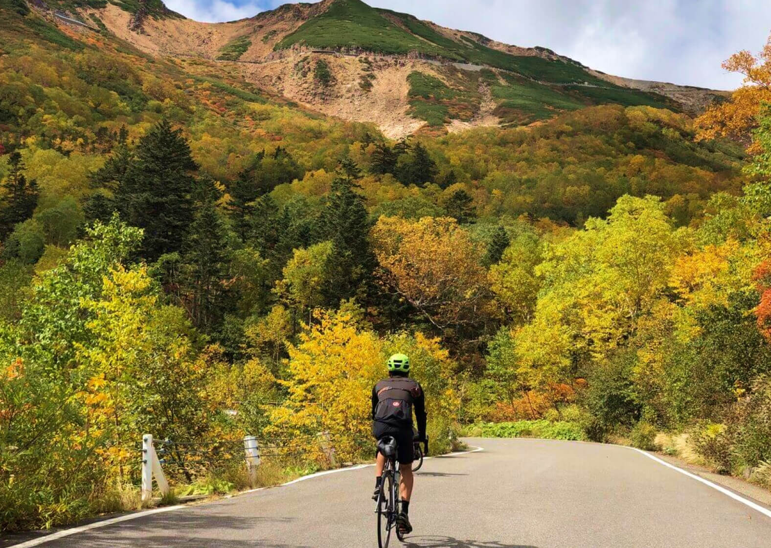 紅葉の山をサイクリングする男性の写真
